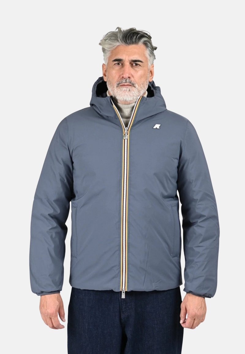 Veste matelassée grise avec capuche, dotée d'une fermeture éclair frontale avec des accents multicolores et un petit logo sur la poitrine. Tissu épais et isolant.