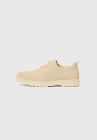 Beige suede lace-up shoes with a rounded toe, textured surface, and a chunky white rubber sole featuring a tread pattern.