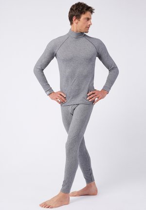 Camiseta térmica gris de manga larga con cuello alto y pantalones ajustados a juego, fabricados en un tejido suave y elástico. Los detalles de costura acentúan el diseño.