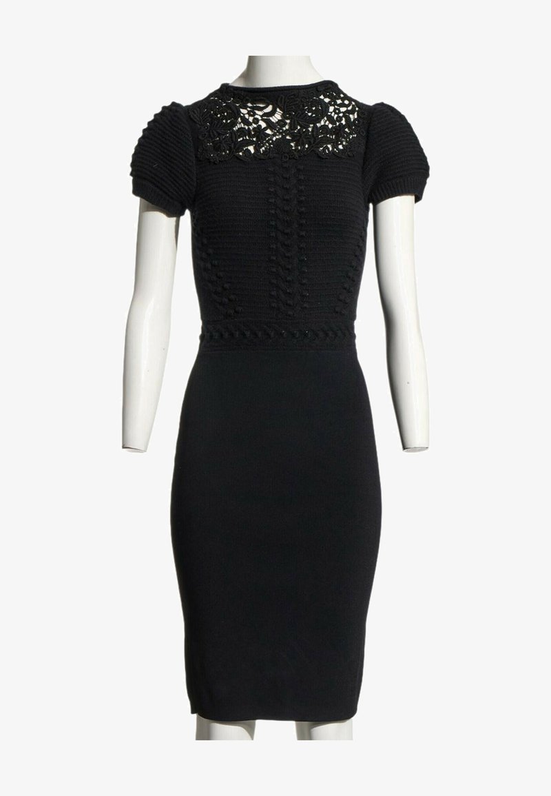 Robe noire cintrée avec manches bouffantes courtes, corsage en maille texturée et empiècement en dentelle florale sur un mannequin blanc.