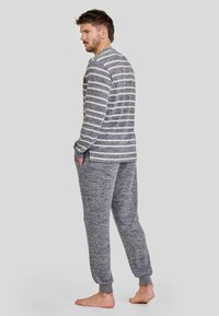 Camiseta de manga larga a rayas en gris y blanco con cuello redondo; combinada con pantalones de chándal en gris jaspeado a juego con puños en los tobillos y bolsillos.