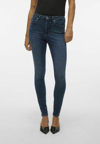 Jeans skinny in denim blu scuro, con cinque tasche, chiusura a zip e vita a media altezza. Texture liscia e leggero stretch per comfort.