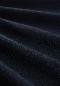 Tissu bleu marine avec une surface douce et texturée. Présente des motifs en relief subtils et de légères ondulations, indiquant flexibilité et épaisseur.