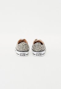 Platnene tenisice s uzorkom leoparda i gumenim potplatima, ukrašene crno-bijelim prugama i oznakom "Converse All Star" na peti.