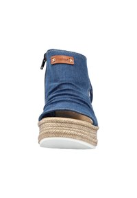 Sandale à talon compensé en denim bleu avec semelle en jute tressée, bout ouvert et fermeture éclair latérale, avec une petite étiquette de marque en cuir marron.