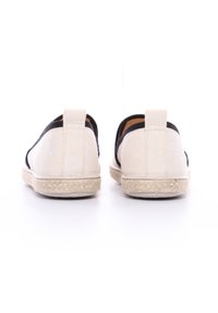Baskets slip-on en toile avec un corps beige, des accents noirs et des semelles en jute de style espadrille ; présente un petit logo à l'arrière.