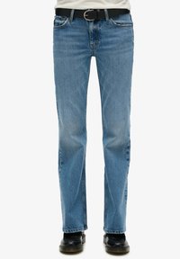 Jeans de mezclilla azul claro con corte recto, que cuentan con cinco bolsillos, costuras sutiles y un cinturón negro con una hebilla plateada.