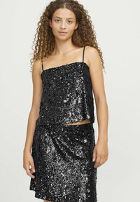 Completo due pezzi nero con top di paillettes caratterizzato da spalline sottili e una gonna coordinata di paillettes. Tessuto liscio, superficie lucida, senza motivi.