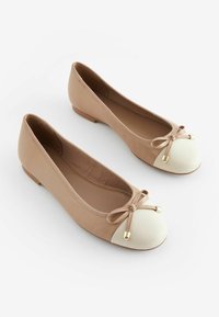 Ballet-tossut vaaleanruskeasta nahasta, joissa on valkoinen pyöreä varvasosa, rusett yksityiskohtana ja kultaiset korostukset kärjessä. Litteä pohja.