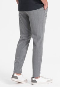 Pantaloni a quadri grigi realizzati in un tessuto dalla trama liscia, con un design slim fit e tasche laterali, abbinati a sneakers bianche.