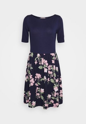 Tummansininen mekko, jossa on lyhyet hihat, istuva yläosa ja levenevä helma, koristeltu vaaleanpunaisella ja vihreällä kukkakuviolla, valmistettu pehmeästä kankaasta.