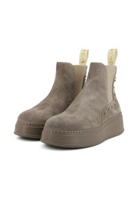 Stivaletti in suede color taupe con suola piatta chunky. Presentano pannelli elastici laterali e borchie decorative lungo i lati. Anelli dorati per la trazione.