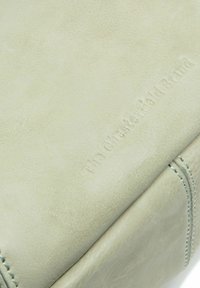 Borsa in pelle verde chiaro con superficie testurizzata, caratterizzata da logo impresso e cuciture a contrasto lungo i bordi.