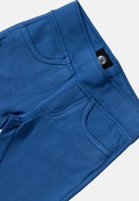 Las leggings de algodón azul cuentan con una textura suave, cintura elástica, bolsillos frontales y un botón decorativo en la cintura.