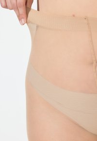 Nackte, durchsichtige Unterwäsche mit einem weichen, dehnbaren Bund. Das Material ist transparent mit einer glatten Textur und minimalen Nähten.