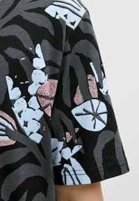 Tricou negru cu mânecă scurtă, având un model floral abstract îndrăzneț în nuanțe de gri, albastru deschis și roz, cu o textură netedă.