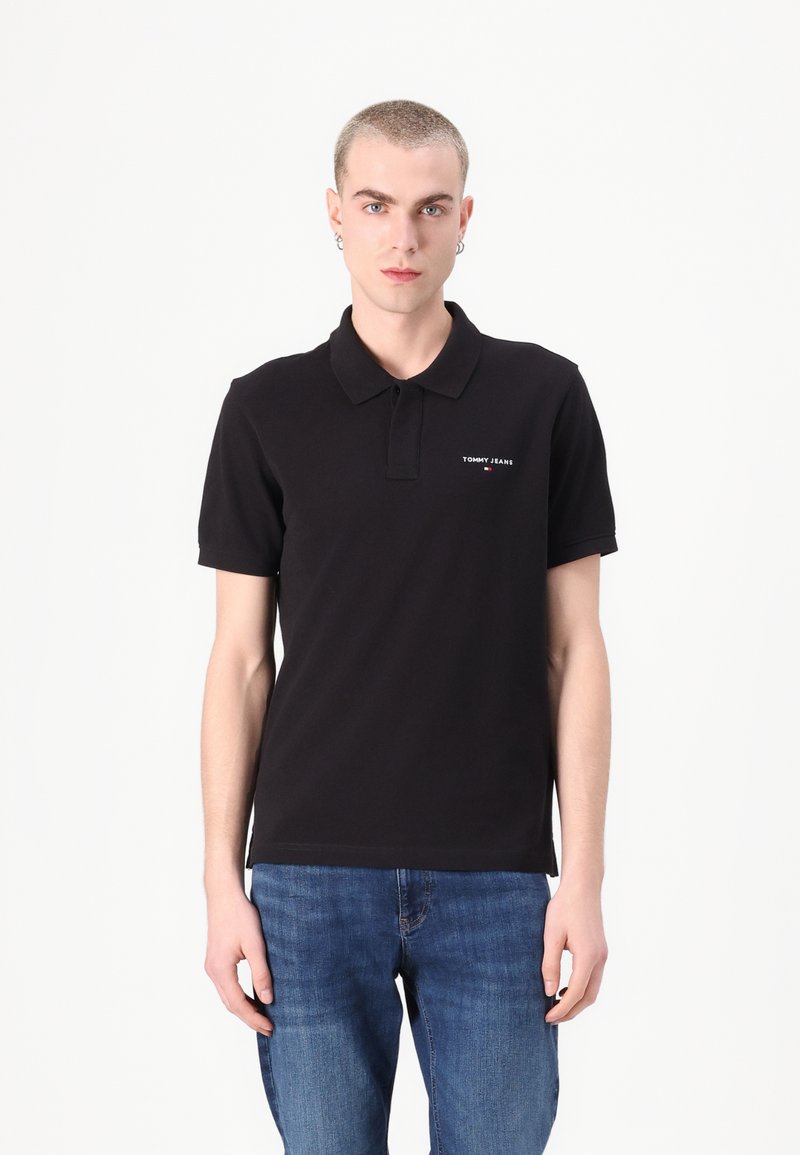 Polo shirt negru din bumbac, cu guler, mâneci scurte și detaliu logo pe față. Asortat cu blugi din denim albastru.