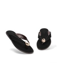 Chanclas negras con una tira texturizada y un acento circular dorado. Material suave con una suela plana, ofreciendo un diseño minimalista.