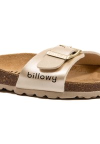 Sandale beige clair avec une semelle en liège, dotée d'une large sangle avec une boucle en métal et du texte en relief "billowy". Fini en cuir texturé.