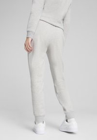 Graue, taillierte Jogginghosen aus weichem Stoff mit strukturiertem Finish, mit elastischen Bündchen und Seitentaschen, kombiniert mit weißen Sneakers.