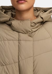 Beige pufferjack met een capuchon, een quilted ontwerp en gestikte details. Gemaakt van een gladde, lichte stof.
