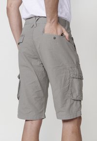 Shorts cargo gris en tissu léger, dotés de poches latérales, d'une fermeture à bouton et d'une coupe décontractée. Texture et coutures visibles.