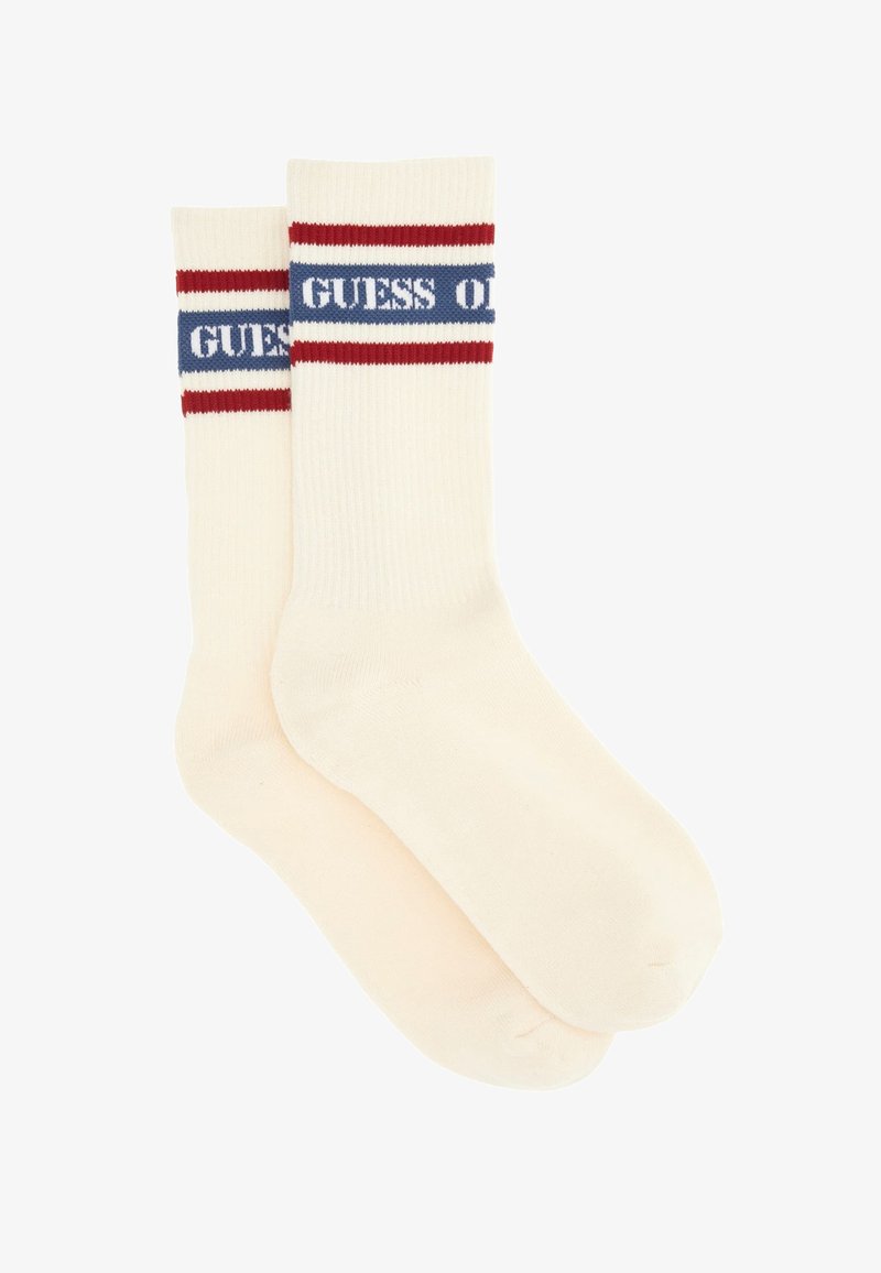 Calzini color crema con texture a coste, con accenti a strisce rosse e blu nella parte superiore e il testo "GUESS" in blu.