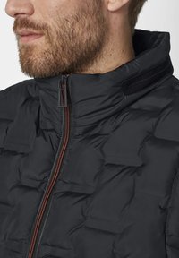 Schwarze gepolsterte Jacke mit hohem Kragen, ausgestattet mit einem Reißverschluss vorne und kontrastierenden orangefarbenen Akzenten. Glatte Textur, leichtes Design.