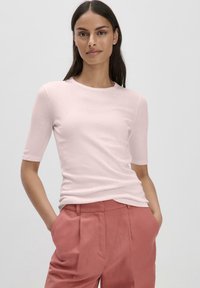 Lichtroze top met korte mouwen en een ronde hals, gecombineerd met hoogwater, geplooide roze broeken. Gladde textuur, minimalistisch ontwerp.