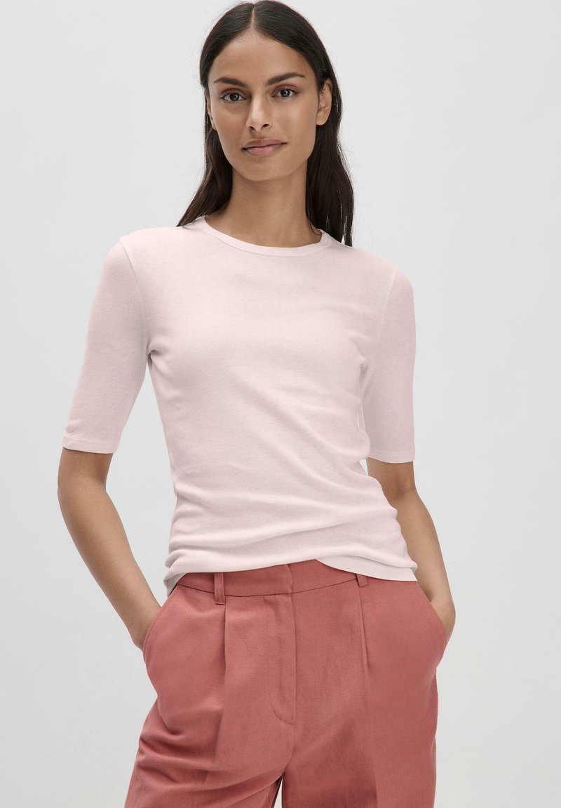 Lichtroze top met korte mouwen en een ronde hals, gecombineerd met hoogwater, geplooide roze broeken. Gladde textuur, minimalistisch ontwerp.