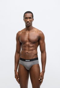 Chiloți gri din bumbac cu talie neagră pe care este inscripționat logo-ul "BOSS". Design ajustat, talie medie, textură netedă și detalii cusute.