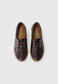 Brown leather shoes with a smooth texture, round toe, lace-up design, and gold eyelets, featuring a light-colored rubber sole.