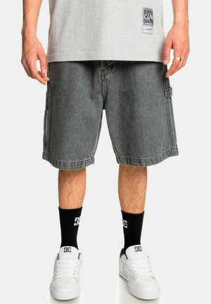 Pantalones cortos cargo de mezclilla gris con bolsillos laterales, detalles de costura y un corte relajado. Combinados con zapatillas blancas y calcetines negros.