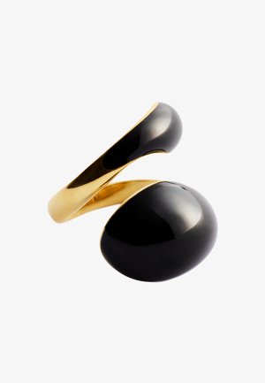 Anello aperto in oro con due grandi pietre ovali nere lisce alle estremità, lucide e riflettenti su uno sfondo bianco.