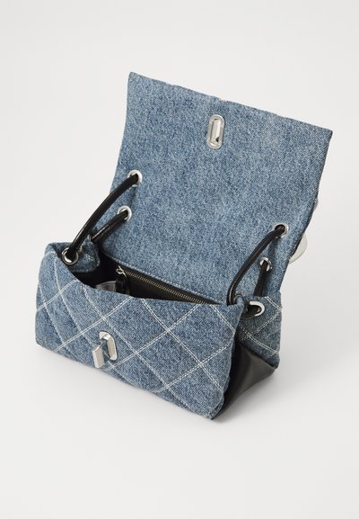 Geantă din denim cu bază din piele neagră, detalii matlasate, accesorii din argint și închidere cu șnur. Designul deschis dezvăluie un interior în contrast.