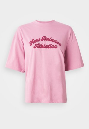 T-shirt rose à manches courtes, col rond, avec le texte "New Balance Athletics" en cursive rouge gras sur la poitrine, sur un fond blanc.