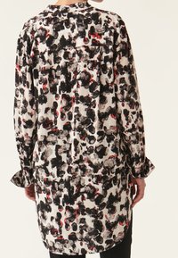 Camicia a maniche lunghe, con bottoni, in un motivo multicolore di macchie nere, bianche e rosse. Tessuto leggero con una vestibilità comoda e un dettaglio di yoke sulla schiena.