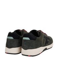 Sneaker in suede verde con dettagli in pelle nera, suola rosa e nera, retro testurizzato e lacci con motivo. Marchio ecologico visibile.