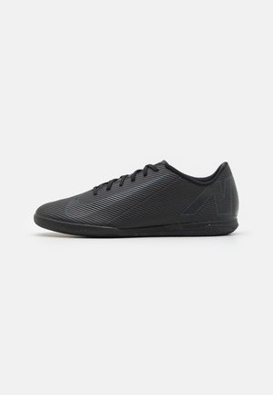 Black low-profile athletic shoe with subtle textured stripes, laces, and a minimalist design on a white background.