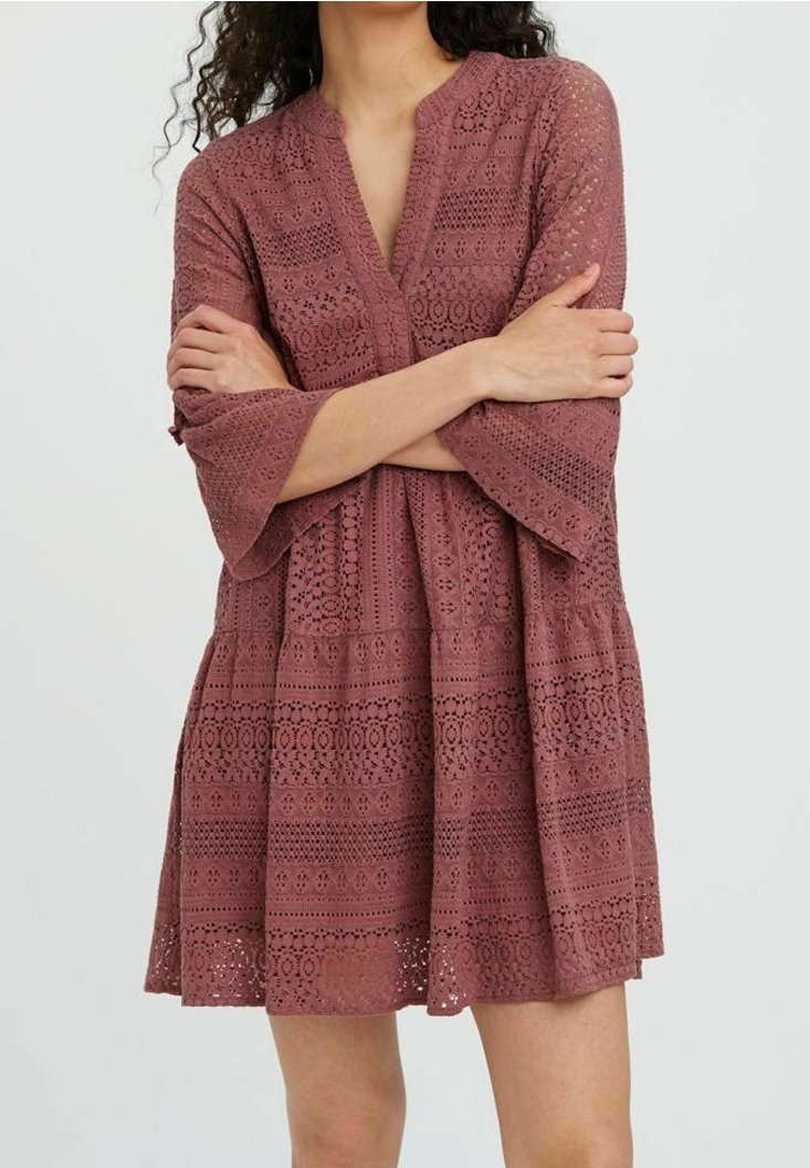 Robe rose en dentelle avec des motifs découpés, des manches évasées et un décolleté en V, dotée de couches de tissu texturé.