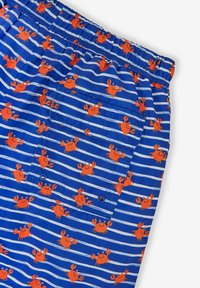 Blaue Shorts mit weißen und blauen Streifen, die ein wiederholtes Muster von orangefarbenen Krabben zeigen. Elastischer Bund und Rücktasche.