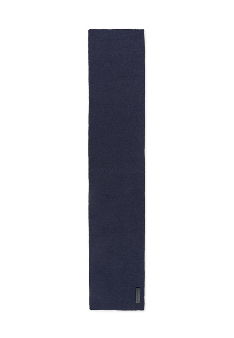 Granatowy prostokątny szalik z małą czarną metką zszytą blisko jednego końca na białym tle.