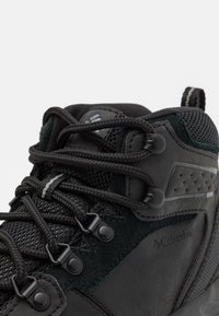 Schwarze Wanderschuhe zeichnen sich durch eine Kombination aus glatten und strukturierten Materialien, Netzpaneelen, einem auffälligen Schnürsystem und verstärkten Zehenkappen aus.