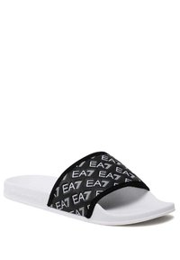 Chancla negra de diapositiva con una tira ancha que presenta un patrón de logo en blanco repetido, suela blanca y textura suave. Diseño de punta abierta.