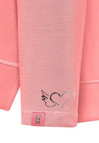 Lichtroze sweatshirt met een gladde textuur; heeft een zilveren hart- en vleugelafbeelding dichtbij de zoom en een klein merklabel aan de onderkant.