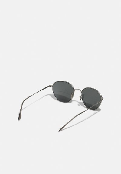 Ochelari de soare cu un cadru metalic subțire, lentile ovale de culoare gri închis și un design elegant, minimalistic. Au brațe subțiri și fără accente hardware vizibile.
