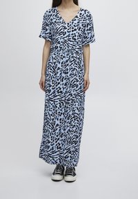 Maxiklänning i ljusblått med svart djurmönster, V-ringning, kort ärm, cinchad midja, svängd tyg, matchad med svarta sneakers.