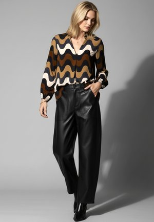 Brown, cream, and black patterned blouse with a V-neck and elastic cuffs; paired with high-waisted, wide-leg black leather pants.
