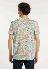 Korte mouwen T-shirt met een lichtgroene achtergrond en een tropisch bloemenpatroon in tinten van oranje, roze en paars.