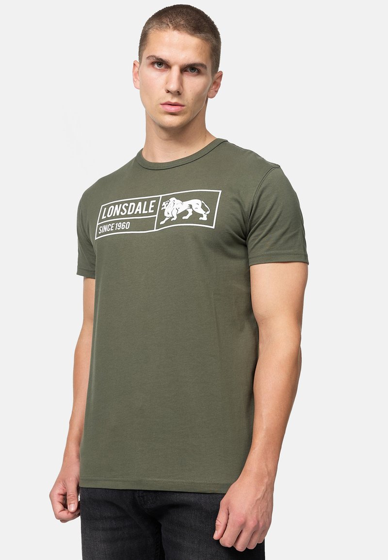 Ελιξερ πράσινο κοντομάνικο T-shirt από βαμβάκι, με λευκό λογότυπο και εκτύπωση κειμένου. Σχεδίαση με στρογγυλή λαιμόκοψη και εφαρμοστή σιλουέτα.